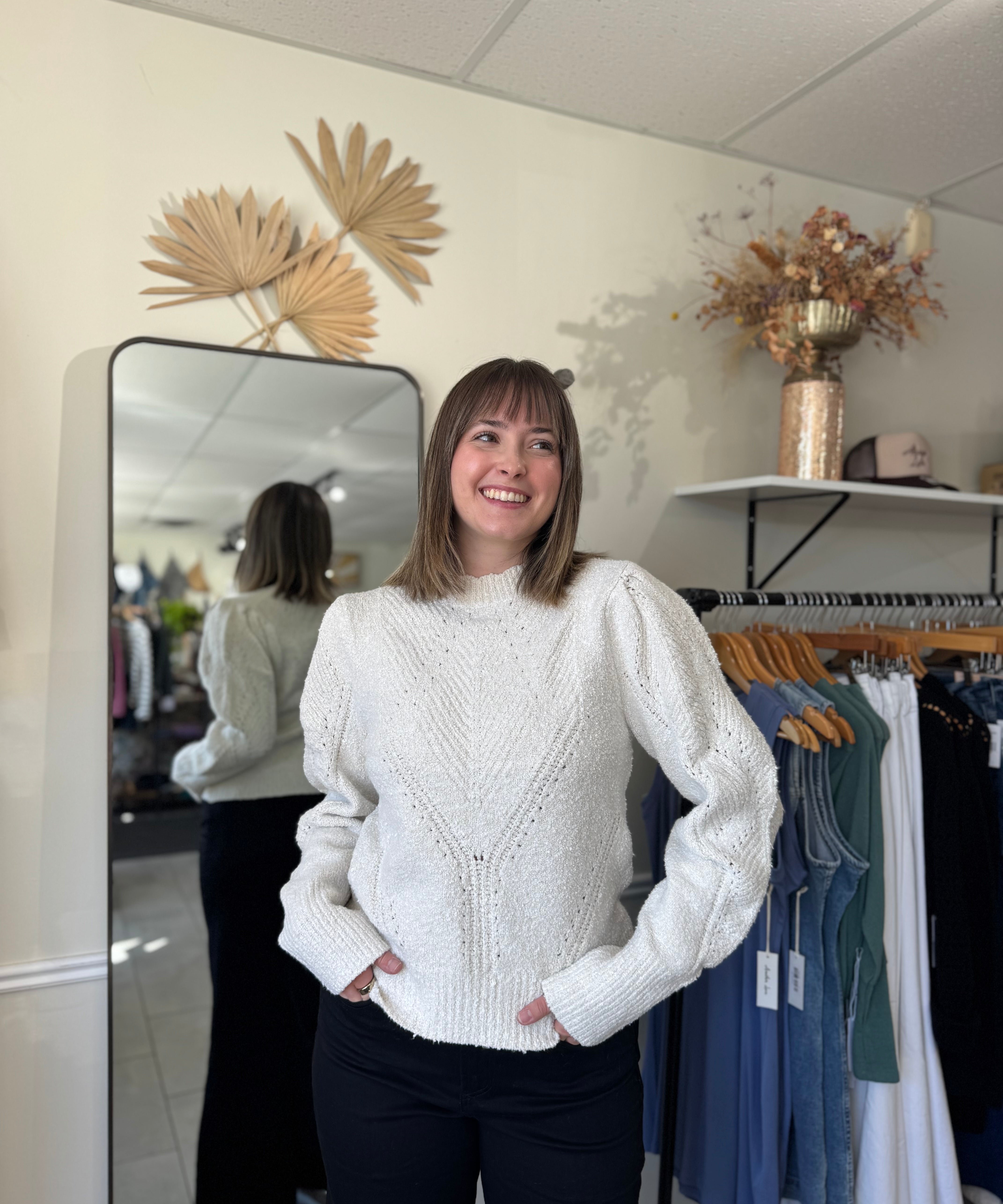 Model wearing an ivory sweater with intricate stitching and puffed sleeves.