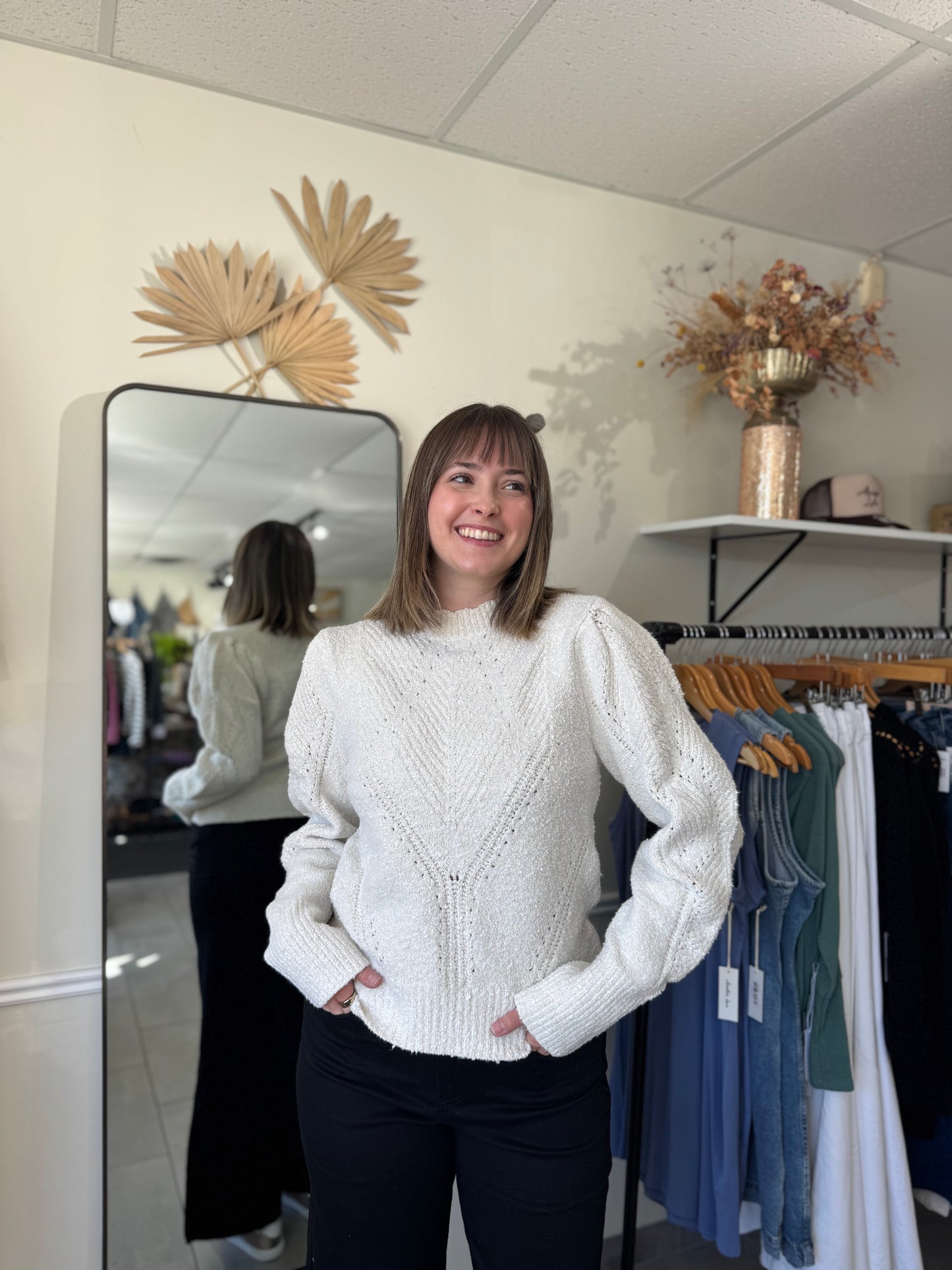 Model wearing an ivory sweater with intricate stitching and puffed sleeves.