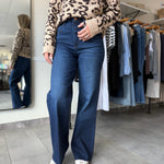 Woman wearing dark wash wide leg denim paired with leopard print sweater.