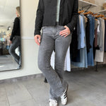 Woman wearing a black suede jacket and washed black, bootcut jeans.