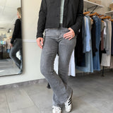 Woman wearing a black suede jacket and washed black, bootcut jeans.
