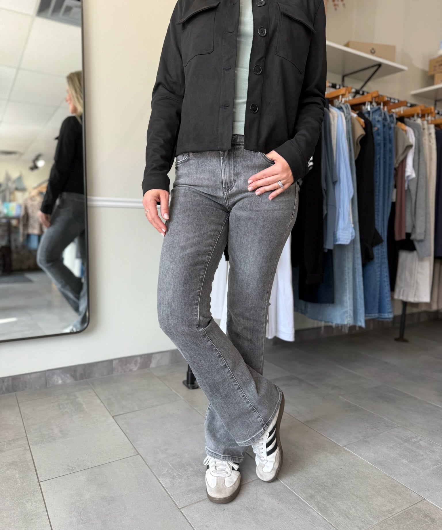 Woman wearing a black suede jacket and washed black, bootcut jeans.