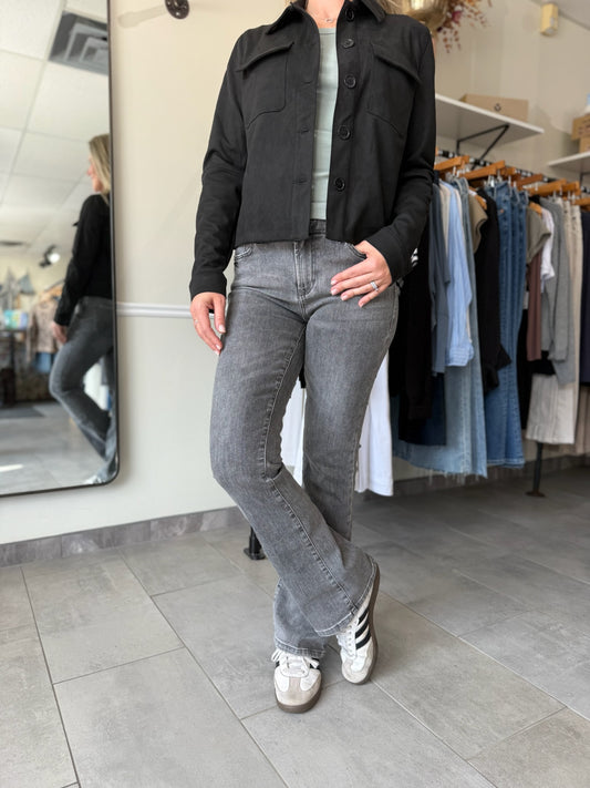 Woman wearing a black suede jacket and washed black, bootcut jeans.