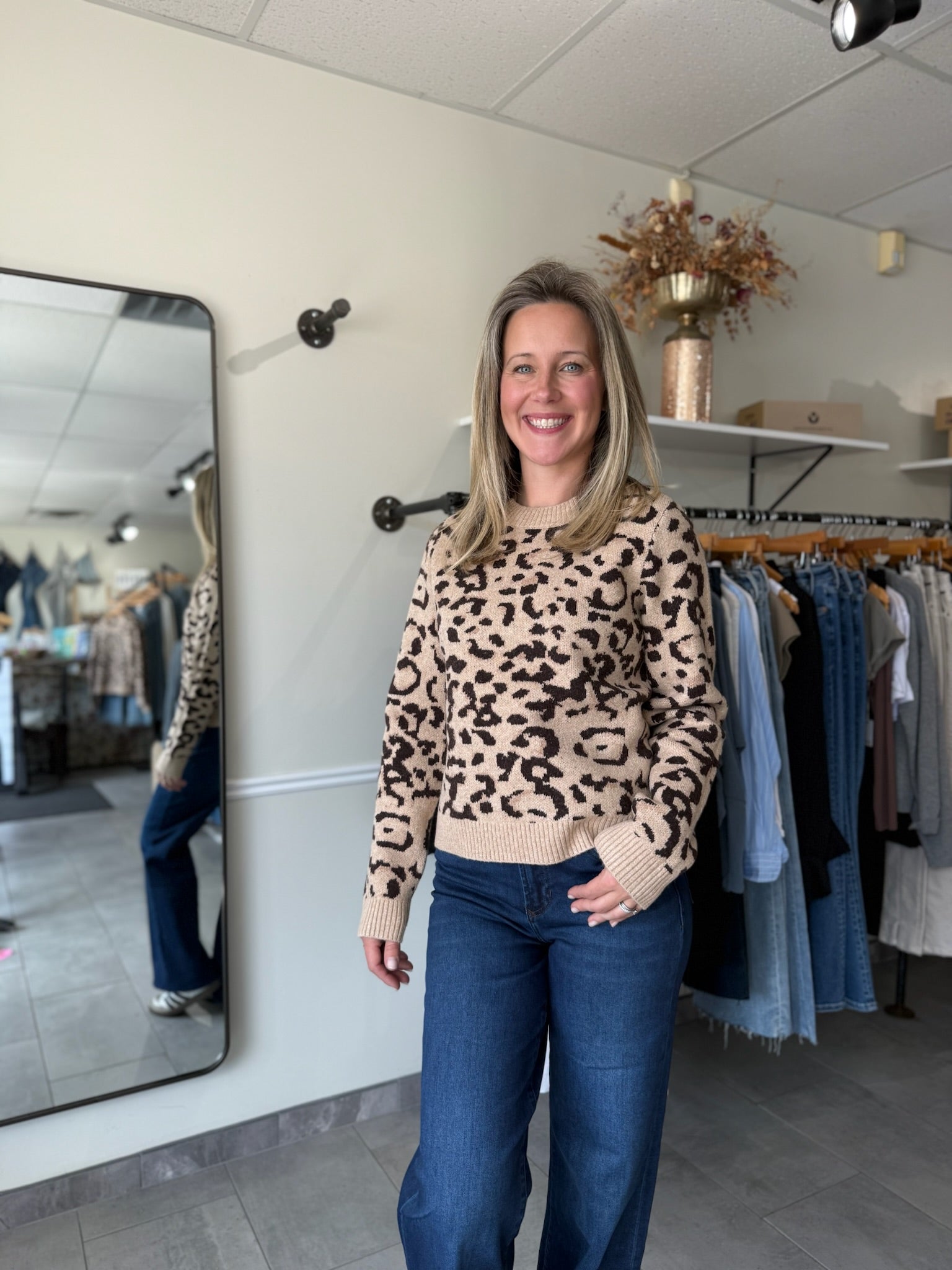 Woman wearing a leopard print sweater and blue jeans in a clothing store.