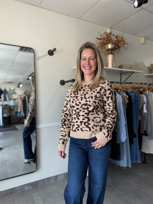 Woman wearing a leopard print sweater and blue jeans in a clothing store.