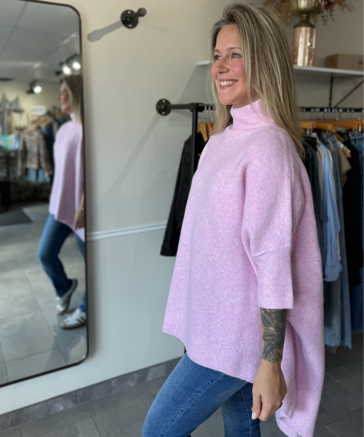 woman wearing a light pink oversized tunic sweater paired with denim.