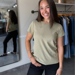 Woman wearing a light green t-shirt and black pants.
