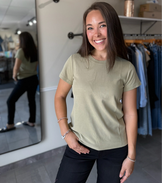 Woman wearing a light green t-shirt and black pants.