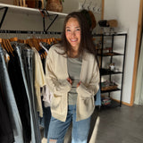 Woman wearing a cream oversized open cardigan with green basic tee shirt.