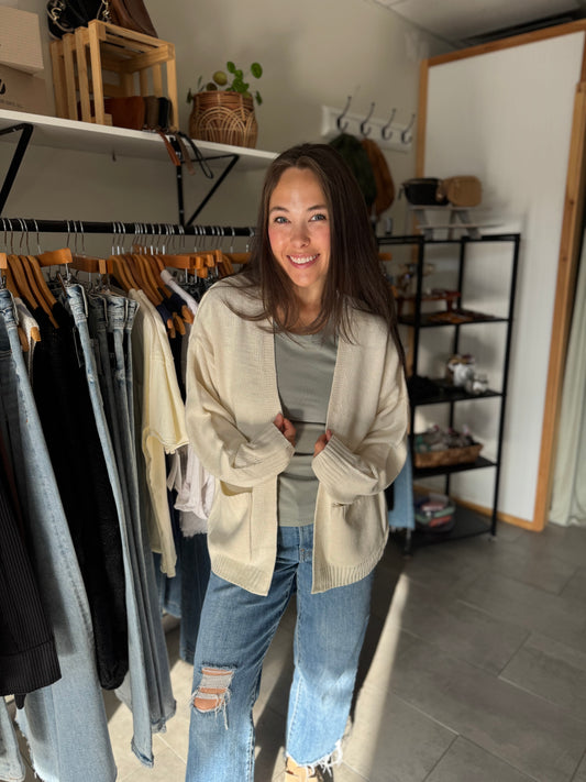 Woman wearing a cream oversized open cardigan with green basic tee shirt.
