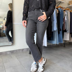 Woman wearing washed black denim with an embroidered detail top.