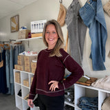 Model wearing bordeaux colored sweater with white stitching.