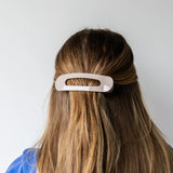 Person with long hair wearing a beige kaxi lay down claw clip.