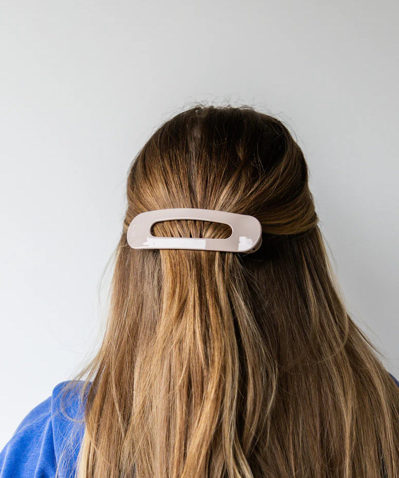 Person with long hair wearing a beige kaxi lay down claw clip.