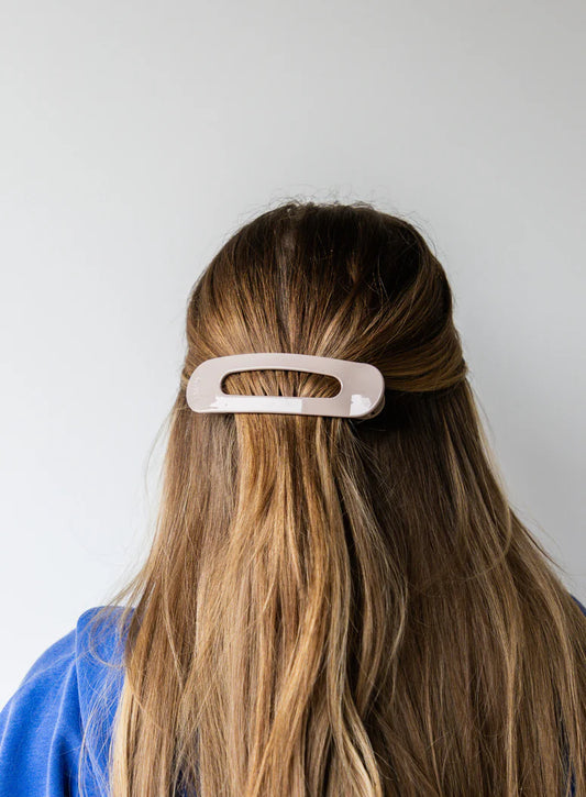 Person with long hair wearing a beige kaxi lay down claw clip.