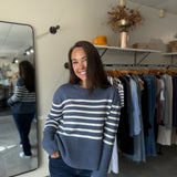 Woman wearing a blue and white striped sweater paired with medium wash denim.