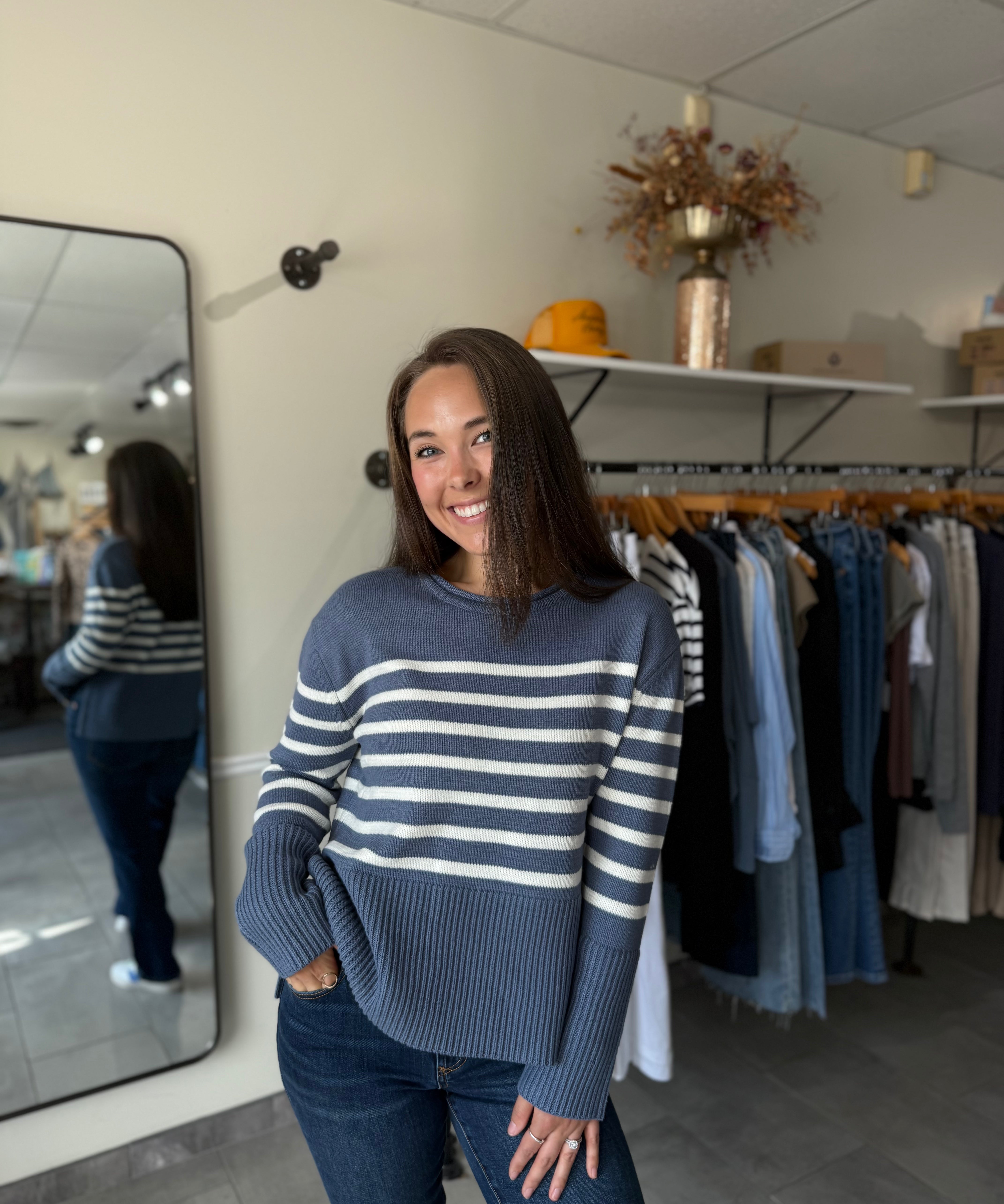 Woman wearing a blue and white striped sweater paired with medium wash denim.