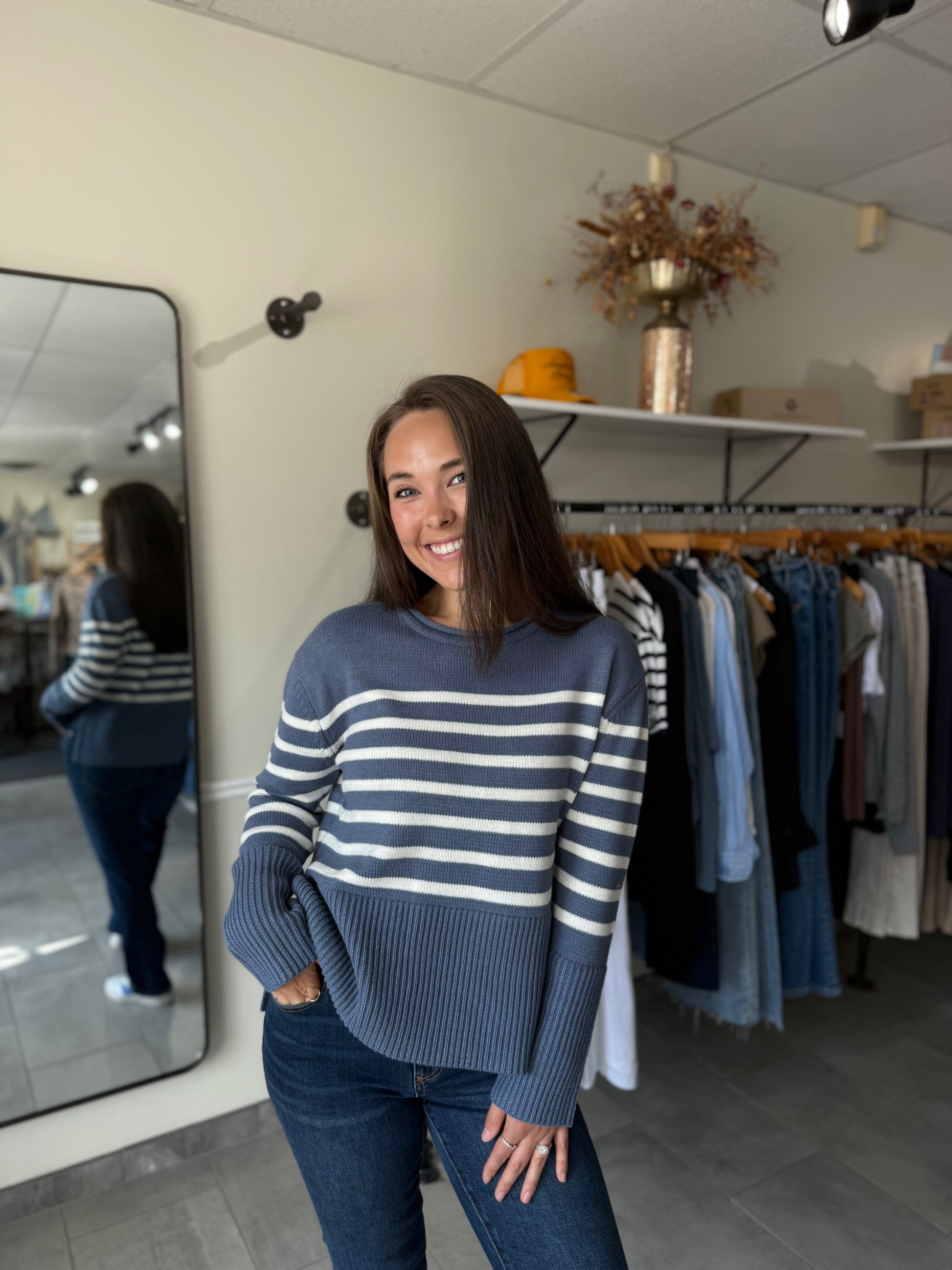 Woman wearing a blue and white striped sweater paired with medium wash denim.