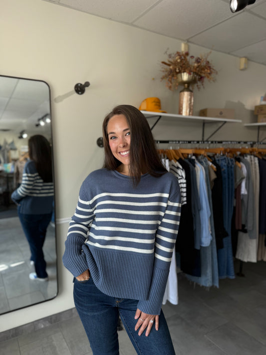 Woman wearing a blue and white striped sweater paired with medium wash denim.
