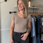 Woman wearing a fitted, beige, seamless t-shirt paired with black denim.