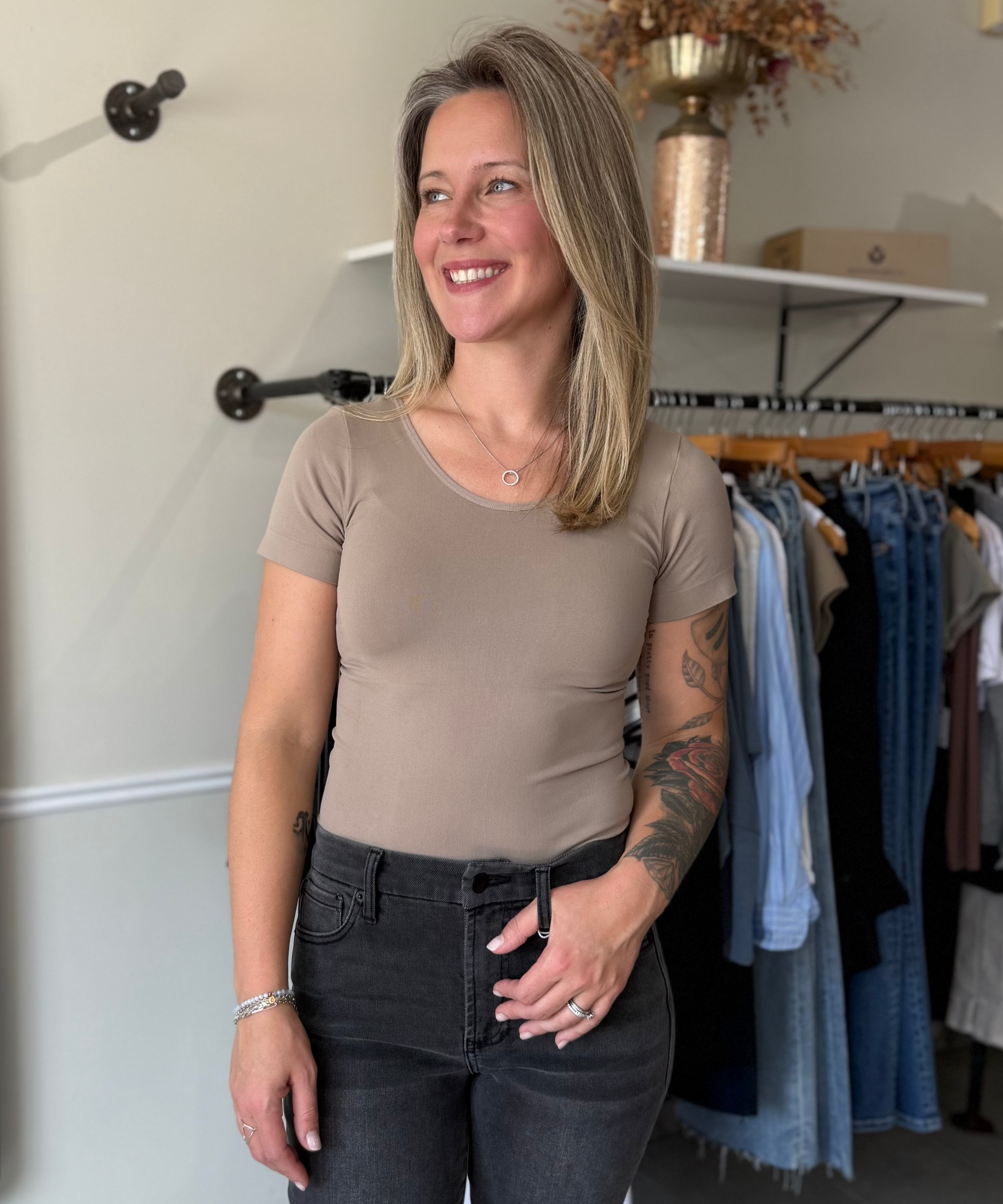 Woman wearing a fitted, beige, seamless t-shirt paired with black denim.