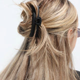 Close-up of a person with blonde hair tied back with a matte black kaxi midi hold everything claw clip.