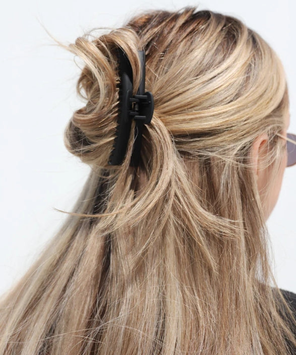 Close-up of a person with blonde hair tied back with a matte black kaxi midi hold everything claw clip.