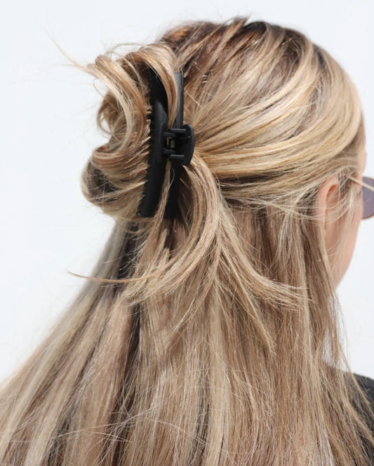 Close-up of a person with blonde hair tied back with a matte black kaxi midi hold everything claw clip.