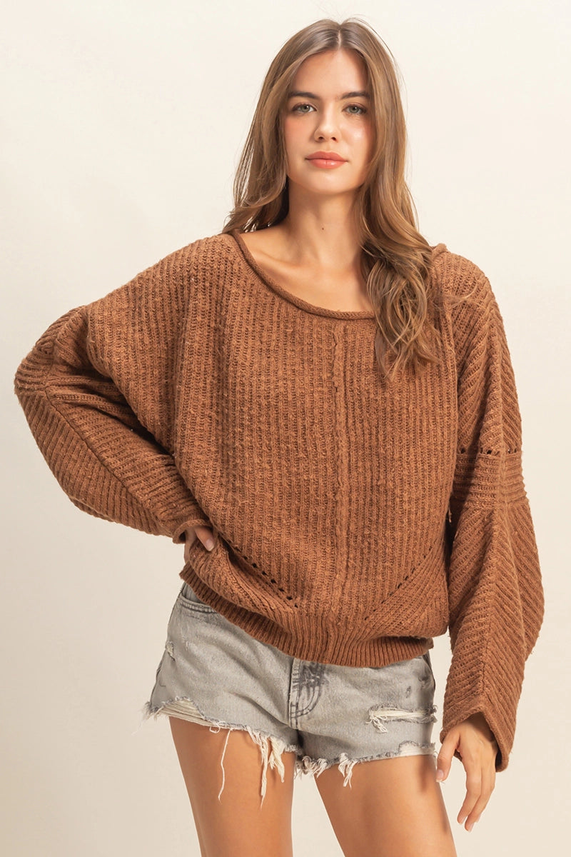 Woman wearing a drop-shoulder, rib knit brown sweater with an oversized fit.