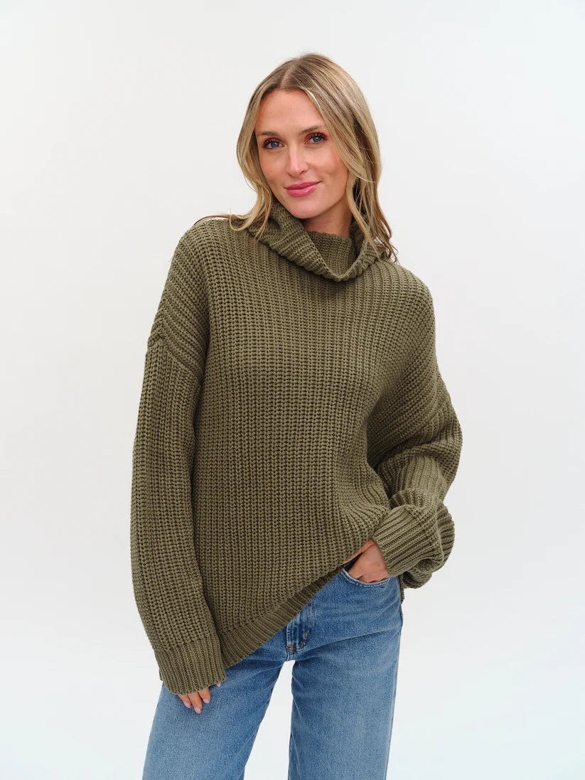 Woman wearing a green knitted sweater with turtle neck and oversized fit from Six Fifty
